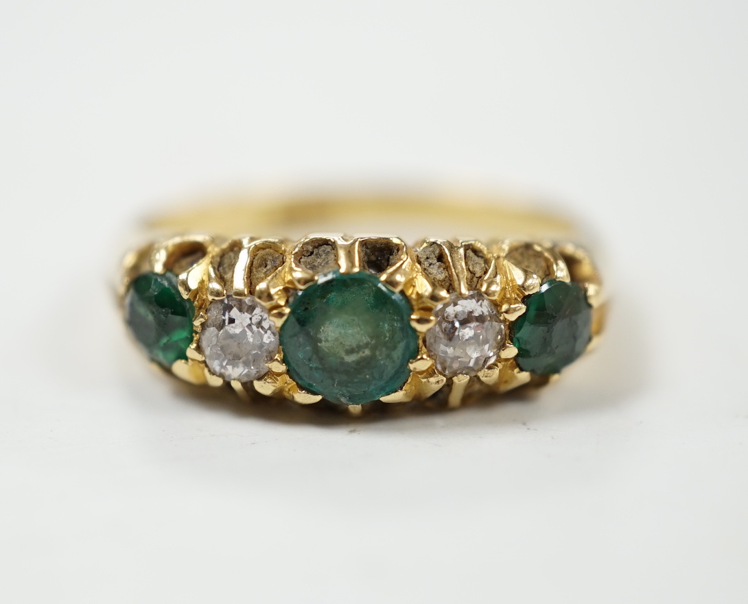 An early 20th century 18ct, three stone green garnet and two stone diamond claw set half hoop ring, size L, gross weight 4.8 grams.